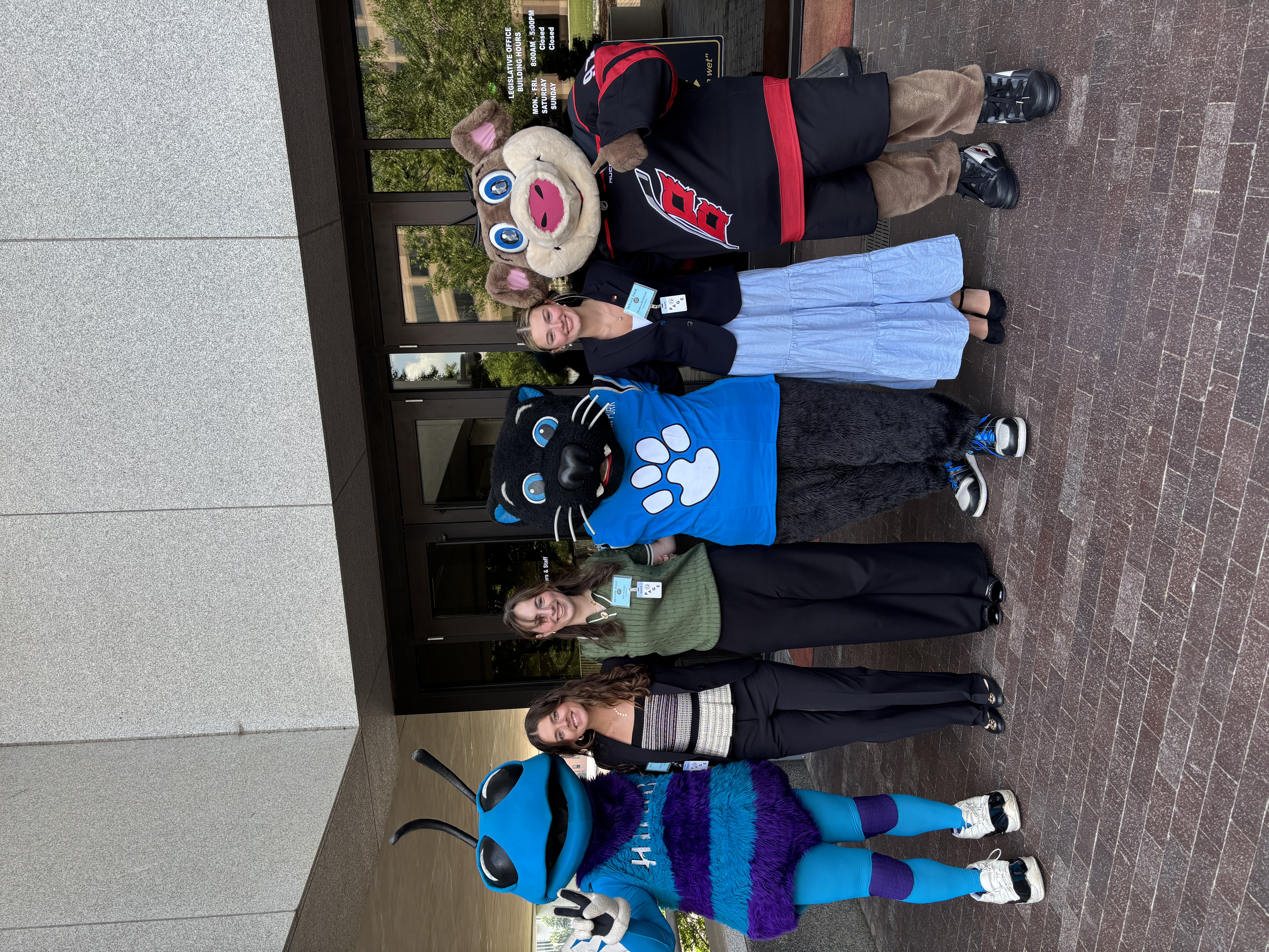 Pages standing in front of the Legislative Office Building with three animal mascots.